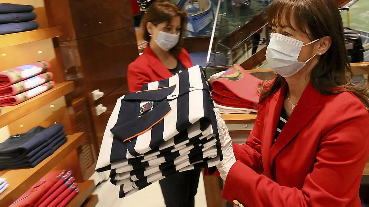 Women with protective masks are preparing to open a store in Vienna, Austria, Tuesday, April 14, 2020. Smaller Austrian shops may reopen with special protective measures from Tuesday on. The Austrian government has moved to restrict freedom of movement for people, in an effort to slow the onset of the COVID-19 coronavirus. The new coronavirus causes mild or moderate symptoms for most people, but for some, especially older adults and people with existing health problems, it can cause more severe illness or death. (AP Photo/Ronald Zak)