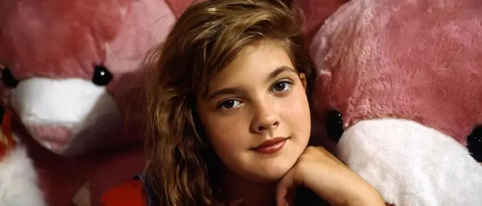 Drew Barrymore als Mädchen zwischen riesigen Kuscheltieren.