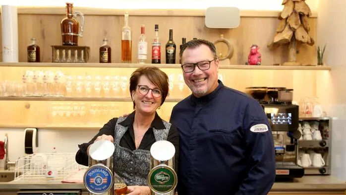 Ein Mann und eine Frau lachen hinter einer Theke