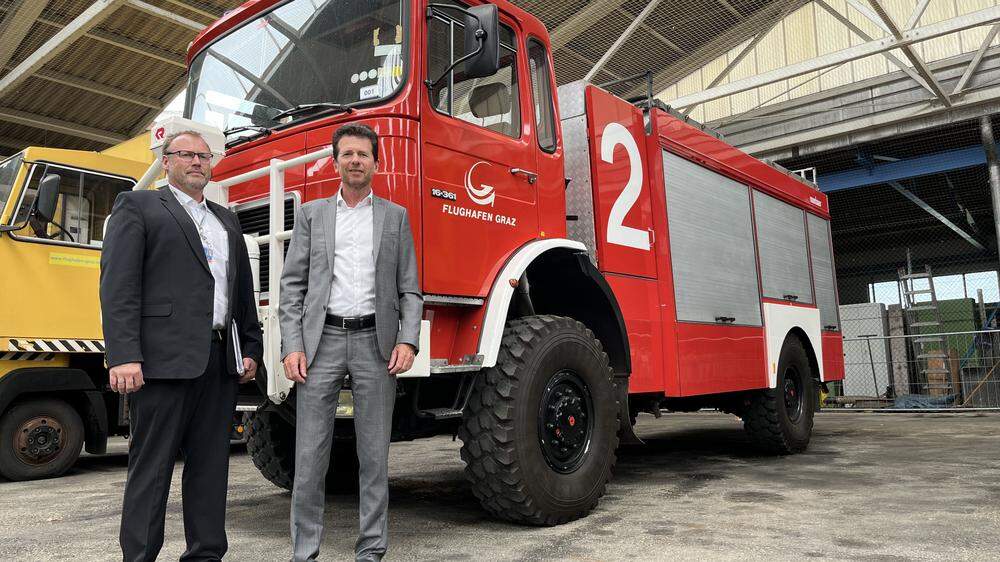 In der Auktionshalle: Flughafen-Geschäftsführer Wolfgang Grimus (rechts) und Flugplatzbetriebsleiter Alexander Greiner vor einem Feuerwehrauto, das zu haben ist