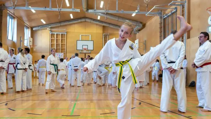 Ein junges Mädchen im Taekwondo-Gewand lächelt in die Kamera.