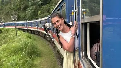 Auf dem Bild sieht man eine Frau aus einem fahrenden Zug lachen, mitten im Dschungel | Das Reisen ist Rebecca Manuels Lust – praktisch durchgehend seit über zwei Jahren