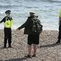 Police officers speak to a man as they patrol the beach in Brighton as the UK continues its lockdown to help curb the spread of coronavirus, in Brighton, England, Saturday April 25, 2020. (Gareth Fuller/PA via AP)