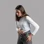 Woman has abdominal pain isolated on a gray background. Young woman suffering from stomach pain. Intestinal and stomach problems concept.