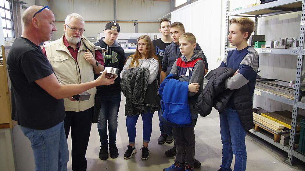 Vorarbeiter Georg Hölblinger zeigt den Schülern und ihrem Lehrer Edgar Karger einen Bauteil vor und nach dem Fräsen