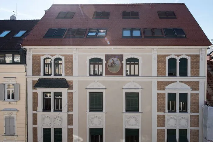 Die Fassase wurde detailgenau restauriert. Die neuen Dachflächenfenster verschwinden optisch hinter fixmontierten, rotgefärbten Rahmenlamellenenelemten.