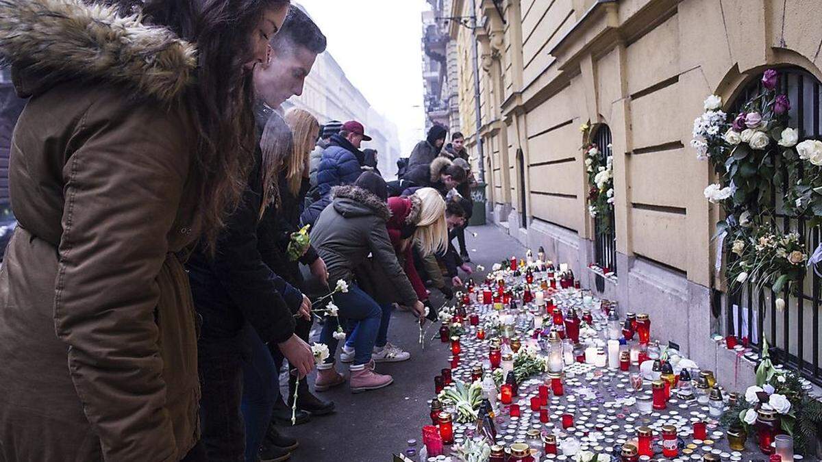 Menschen platzieren Kerzen und Blumen vor dem Gymnasium in Budapest