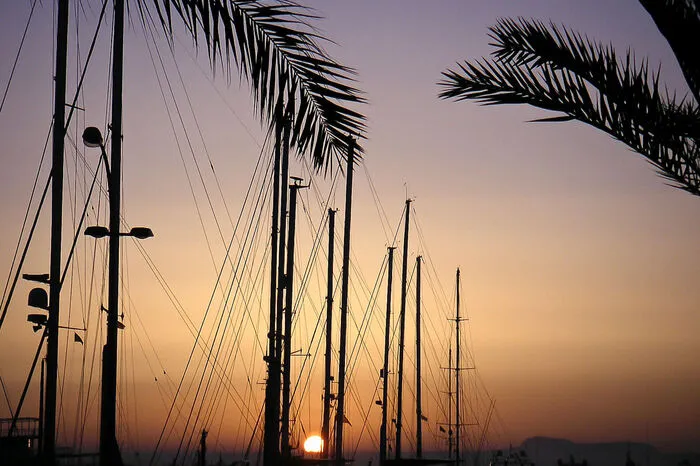 Sonnenaufgang im Hafen von Palma. Der Hafen von Palma ist idealer Ausgangspunkt für Bootsausflüge und Fähren zum Festland. Er spiegelt aber auch gleichermaßen die Geschichte und den Wandel der Insel wider. Bevor das rege Touristentreiben am Hafen beginnt, lohnt es sich für Reisende den Wecker früh zu stellen und sich den Sonnenaufgang dort anzusehen: Ein unvergessliches Farbenspiel für das Fotoalbum und zugleich ein romantischer Tagesstart. Bei einem anschließenden Bootsausflug lernen Urlauber die Insel vom Wasser aus kennen.