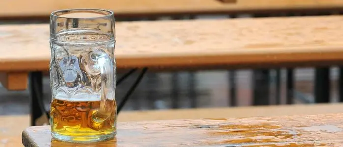 Ein fast leeres Glas Bier steht einsam auf einem Biertisch.