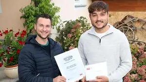 Zwei Männer posieren für ein Foto. Der Mann links hält eine Urkunde in seinen Händen. Es ist eine Urkundenübergabe. | Fabio Weyrer von der TiBo Jugendmusik (rechts) mit Kleine Zeitung-Redakteur Dorian Wiedergut