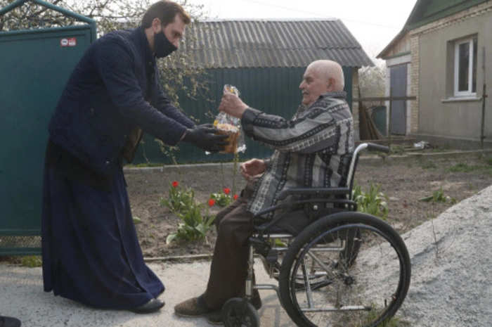 Ein orthodoxer Priester in der Ukraine überreicht einem älteren Mann einen Osterkuchen in der Nähe der Hauptstadt Kiew. 
