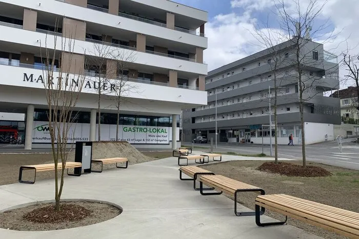 Jüngst haben Arbeiter begonnen, die Freifläche zur Hauptstraße als kleinen Park zu gestalten. Es gibt Wege mit Bänken und Bäume, die in aufgeschütteten Hügeln gesetzt worden sind.