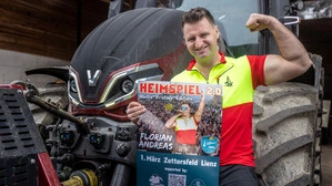 Der Sänger Florian Andreas steht mit einem Plakat vor einem Traktor