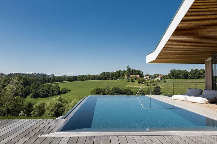 Für eine Extraportion Urlaubsstimmung sorgt auch der Infinity-Pool mit Blick auf den Wald. Er verlängert das Haus und lädt mit seinen Sitzstufen zum ausgiebigen Sonnenliegen ein.