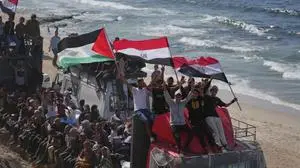 Displaced Palestinians ride on trucks loaded with belongings and wave Egyptian and Palestinian flags as they travel along the coastal road near Wadi Gaza in the central Gaza Strip, moving toward Gaza city, Saturday, Oct. 11, 2025, after Israel and Hamas agreed to a pause in their war and the release of the remaining hostages. (AP Photo/Jehad Alshrafi)