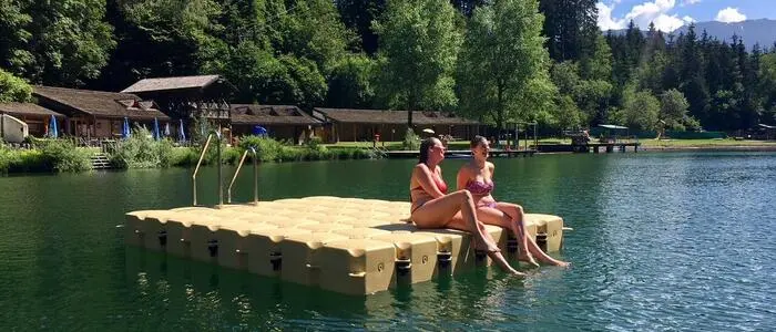 Zwei Frauen sitzen auf einer Schwimminsel im Tristacher See
