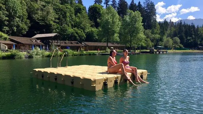 Zwei Frauen sitzen auf einer Schwimminsel im Tristacher See