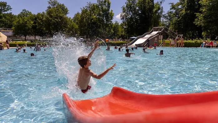 Ein Kind platscht von einer Rutsche ins Becken eines Freibades