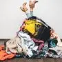 woman legs out of a pile of clothes on the floor. shopping addiction concept