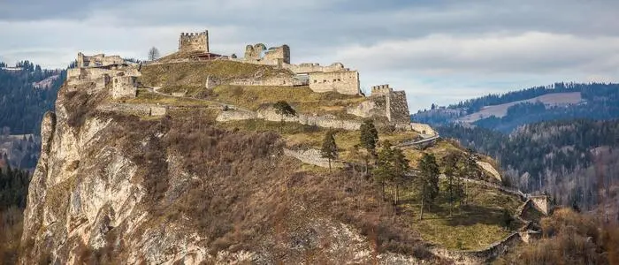 Eine Burgruine mit Bergen im Hintergrund