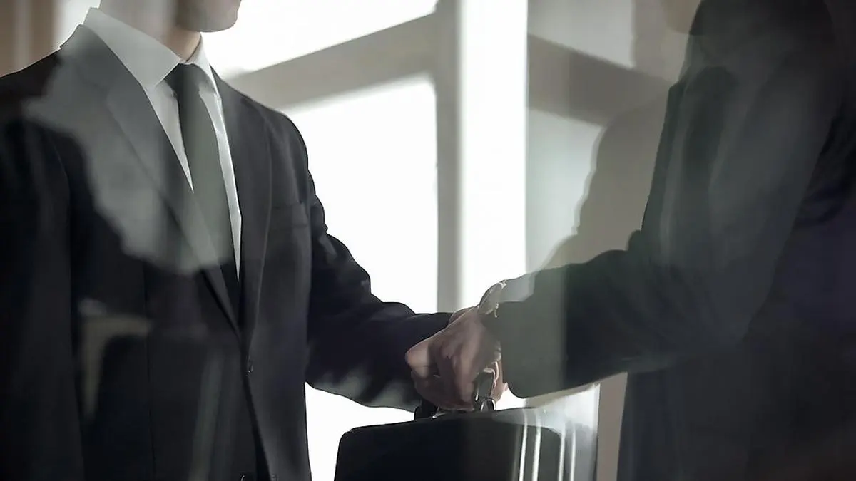 Man handing over briefcase to another man in business suit, secret transfer