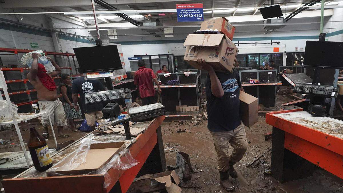 People take goods from a local supermarket after Hurricane Otis ripped through Acapulco, Mexico, Thursday, Oct. 26, 2023. Many residents were taking basic items from stores to survive. Others left with pricier goods, in widespread rampages through the area's stores. (AP Photo/Marco Ugarte)