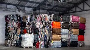 Heap of pressed colorful textile waste packed in bales in store-house