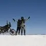 Zwei Motorradfahrer stehen neben ihrem Motorrad in einer Salzwüste