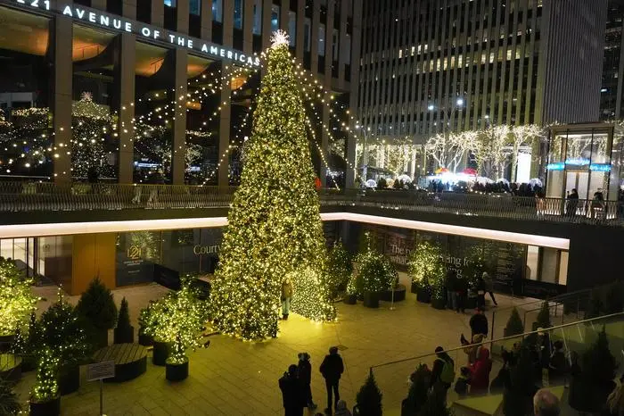 People pose for photos near a Christmas tree on Sixth Avenue Monday, Dec. 22, 2025, in New York. (AP Photo/Frank Franklin II)