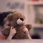 Sad female kid covering face by teddy bear toy, family problem, loneliness abuse