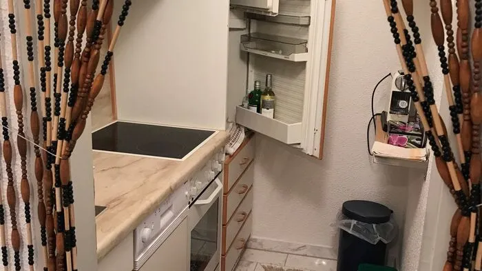 Die Ausgangslage: Grüner Filzboden, dunkle Einbaumöbel und Perlenschnurvorhang als Abtrennung zur Küche.