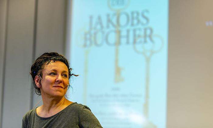 Olga Tokarczuk - dahinter das Cover zu ihrem Buch "Jakobsbücher"