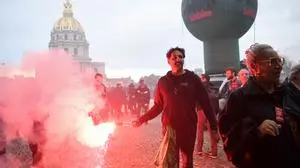 A protester burns a flare during a demonstration in Paris, on October 18, 2022 after the CGT and FO trade unions called for a nationwide strike for higher salaries, and against the government's requisitioning of fuel refineries to force some strikers back into opening fuel depots. - Unions in other industries and the public sector have also announced action to protest against the twin impact of soaring energy prices and overall inflation on the cost of living. (Photo by Bertrand GUAY / AFP)