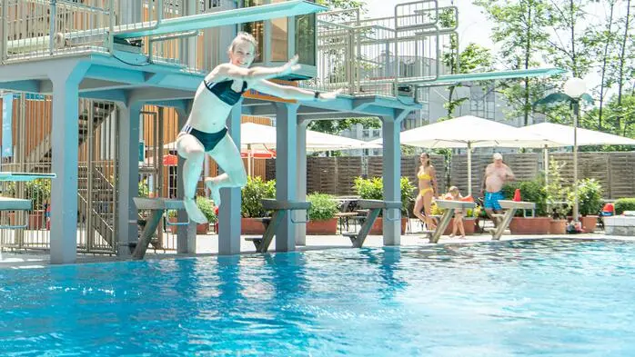 Mädchen springt vom 1-Meter-Brett ins Wasser und ist kurz vorm Eintauchen