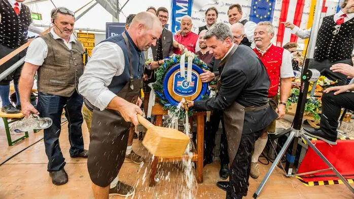Zu sehen sind zwei Männer, die Bier aus einem Fass zapfen
