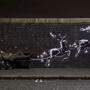 Ein neues Kunstwerk des britischen Street-Art-Künstlers Banksy in Birmingham zeigt auf einer Backsteinmauer zwei fliegende Rentiere, die eine davor stehende Bank zu ziehen scheinen