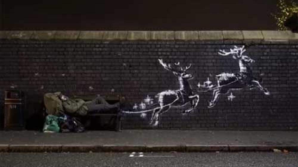 Ein neues Kunstwerk des britischen Street-Art-Künstlers Banksy in Birmingham zeigt auf einer Backsteinmauer zwei fliegende Rentiere, die eine davor stehende Bank zu ziehen scheinen
