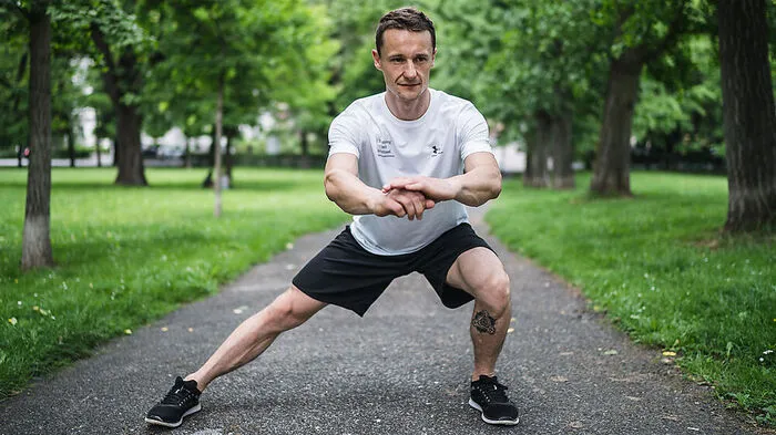 Für diese Übung stehen Sie zunächst in der breiten Grätsche. Dann wird das Körpergewicht zur Seite auf ein Bein verlagert, sodass es sich beugt.Beugen Sie das Knie so weit, bis es sich direkt über Ihren Zehenspitzen befindet. Anschließend drücken Sie sich aus dieser Position durch die Ferse wieder zurück in den Grätschstand.Die Arme strecken Sie dabei am besten vor dem Körper aus. Rücken bleibt gerade.