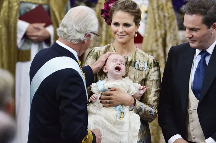 Schwedens König Carl XVI. Gustaf versucht den schreienden Prinz Nicolas zu trösten. Seine Mutter Madeleine hält ihn während der Taufzeremonie.
