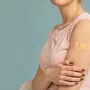 Vaccination against covid-19. Unrecognizable lady showing an adhesive bandage on shoulder after injection