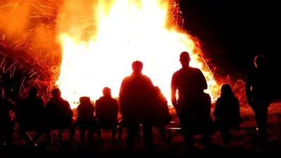 Menschen stehen um ein großes Osterfeuer