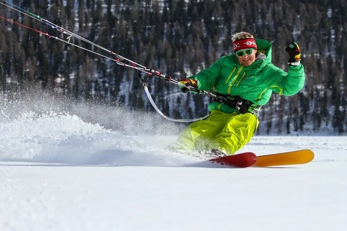 Snowkiten auf dem Silvaplanase. Die neue Trendsportart erobert in den letzten Jahren nicht nur die Herzen eingeschweißter Kitesurfer – auch Skifahrer und Snowboarder, die auf der Suche nach einer abwechslungsreichen und dynamischen Betätigung abseits der präparierten Pisten sind, finden im Snowkiten eine willkommene Alternative. Ausgestattet mit einem Lenkdrachen und Skiern oder Snowboard lässt man sich beim Snowkiten vom Wind über gefrorene Seen, Pulverschneehänge oder auch bergauf bis zum Gipfel ziehen. Grundkenntnisse im Skisport oder im Kitesurfen sind hilfreich, allerdings kein Muss – die trendige Wintersportart eignet sich auch für Anfänger. Die Skischule Wyss Snowsports im Schweizerischen Silvaplana bietet Privatstunden und 5-stündige Ganztags-Abenteuer für Anfänger und geübte Snowkiter an. Auf dem gefrorenen Silvaplanasee lässt man sich dabei vom berühmten Malojawind über das Eis tragen, der den ganzen Winter über für konstant gute Windverhältnisse sorgt.
