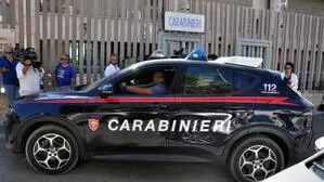 Man sieht ein Auto der Carabinieri und Personen um dieses stehen