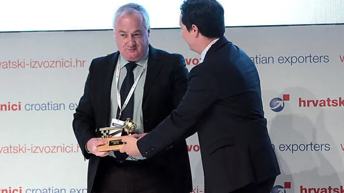 Joseph Gene Petric, beigeordneter Minister des Ministeriums für auswärtige und  europäische Angelegenheiten, überreicht Managing Director Stefan Hillmann den Preis für Wirtschafts- und Entwicklungszusammenarbeit.