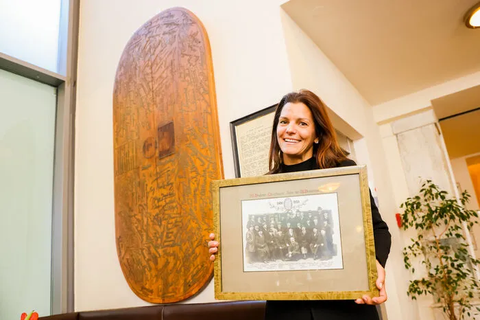 Sandwirth-Chefin Helvig Kanduth mit einem Gruppenbild und dem Drahrer-Tisch. Dieser ist heute an einer Wand montiert.