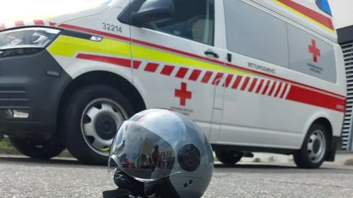 Motorradhelm liegt vor einem Rettungsauto.