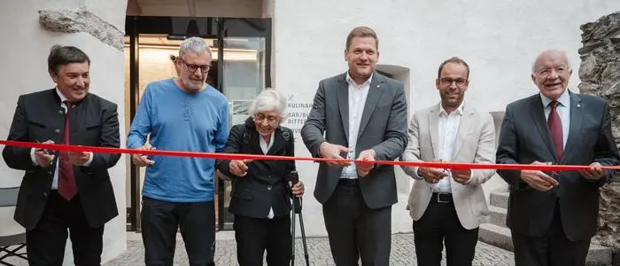 Sechs Personen schneiden ein rotes Band durch