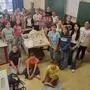 Eine Schulklasse hat sich im Klassenzimmer um ein Modell eines Gartens zusammengestellt und schaut in die Kamera