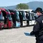 A police officials looks on as bus drivers gather in front of their vehicles as they stage a protest in Zagreb on May 7, 2020, to highlight the impossibility of working due to the spread of the new coronavirus (COVID-19). - Tourism is a key component in the European economy, accounting for 10 percent of all activity but it now faces its greatest challenge -- how to survive the coronavirus pandemic? International tourist arrivals could plunge by 60 to 80 percent in 2020 owing to the coronavirus, the World Tourism Organization warned, meaning the local business is going to be essential. (Photo by Denis LOVROVIC / AFP)