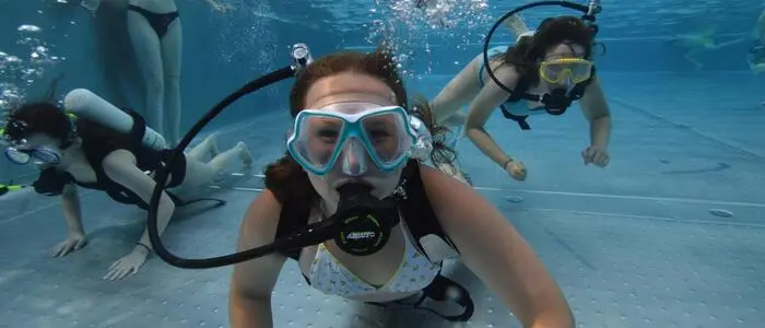 Eine Unterwasseraufnahme von mehreren Kindern mit Tauchermasken und Atemgeräten in einem Pool